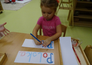 Julcia odrysowuje listery z ruchomego alfabetu.