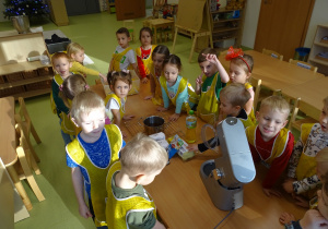 Dzieci stoją wokół stołu, na którym przygotowane są produkty.