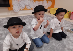 Dzieci w strojach bałwanków z kapeluszami na głowie