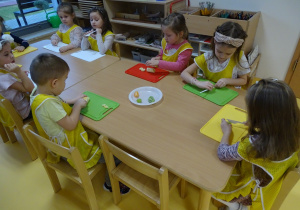 Dzieci kroją owoce i wkładają na talerz