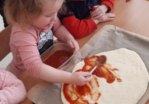Dzieci smarują sosem pizzę