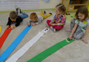 Dzieci wypełniają kształty na wiatraku za pomocą fasoli i pestek dyni.