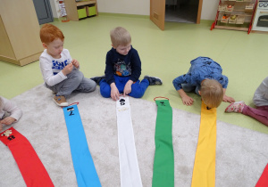 Dzieci wypełniają kształty na wiatraku za pomocą fasoli i pestek dyni.