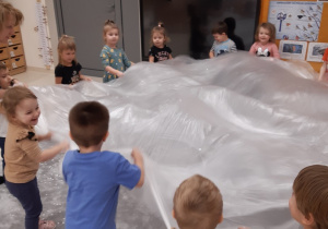 Dzieci podrzucają na folii wycięte z papieru śnieżynki