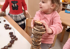 Dzieci budują wieże z plastrów drewna