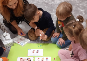 Dzieci odbijają paluszek umoczony w farbie na kodeksie