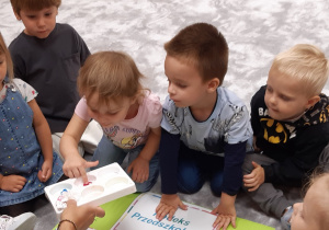 Dzieci odbijają paluszek umoczony w farbie na kodeksie