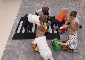 Dzieci bawią się autkami na pasach w sali