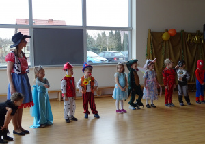 Dzieci przebrane za różne postaci tańczą w kole.