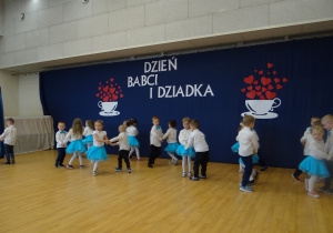 Dzieci tańczą w parach, trzymając się za ręce.