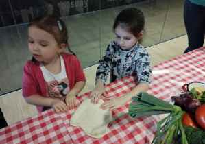 Dzieci pomagają sobie w rozciąganiu ciasta.