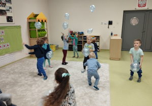 Dzieci bawią się błękitnymi balonami.