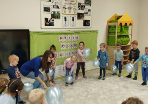 Dzieci z panią tańczą z błękitnymi balonami.