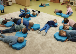 Dzieci leżą na niebieskich poduszkach.