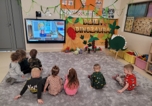 Dzieci oglądają na tablecie film o dinozaurach