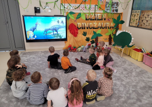 Dzieci oglądają film o dinozaurach