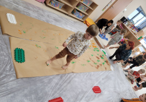 Dziecko idzie po papierze robiąc ślady stopami pomalowanymi farbą