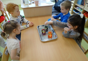 Dzieci wsypują sodę do szklanki.