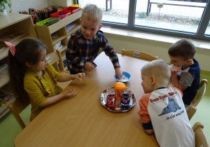 Dzieci wsypują sodę do szklanki i obserwują reakcję z octem.