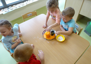 Dzieci wsypują sodę do szklanki i obserwują reakcję z octem.