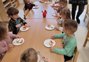Dzieci jedzą ciasto przy stolikach
