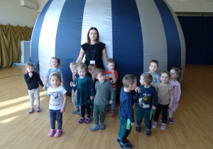 Dzieci z panią stoją przed mobilnym planetarium