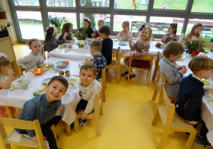 Dzieci siedzą i rozmawiają przy stole wielkanocnym
