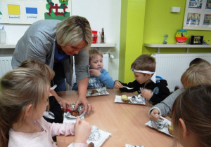 Nauczycielka przekrawa dzieciom ziemniaki na pół