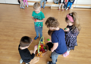 Dzieci szukają kolorowych jajek ukrytych w sali gimnastycznej