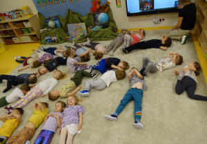Dzieci leżą na podłodze i słuchają odgłosów natury