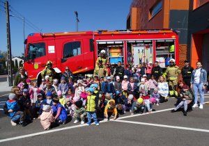 Zdjęcie grupowe dzieci i strażaków przy wozie strażackim