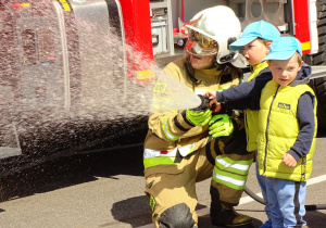 Dzieci leją wodę z węża strażackiego