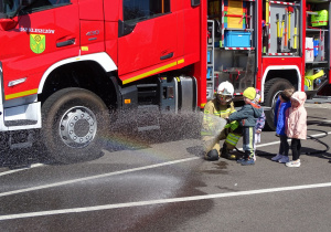 Dzieci leją wodę z węża strażackiego
