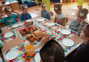Dzieci siedzą przy kolorowo nakrytym stole