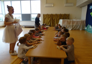 Dzieci siedzą przy stole ze swoimi króliczkami.