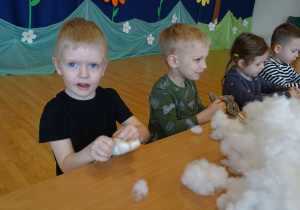 Dzieci wypychają swoje króliczki białym puchem.