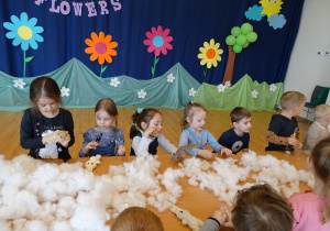 Dzieci wypychają swoje króliczki białym puchem.