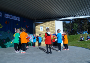Dzieci stoją w kole i tańczą układ choreograficzny