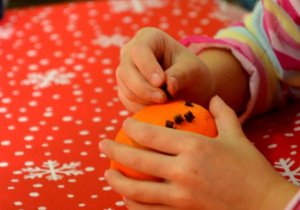 Dziecko dekoruje pomarańcze goździkami