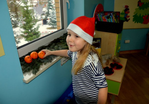 Dziewczynka układa pomarańcze na gałązkach
