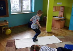 Chłopiec skacze po planszy do gry w klasy