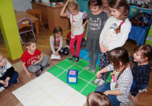 Dzieci grają w grę planszową wykonaną ze zużytych brystoli - utrwalają figury geometryczne