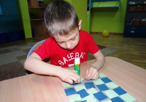 Chłopiec wykleja planszę do gry w warcaby