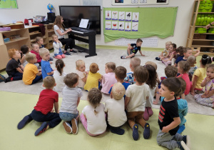 Dzieci słuchają gry na pianinie
