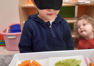 Chłopiec z zasłoniętymi oczami rozpoznaje produkty