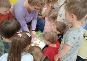 Dzieci oglądają ilustracje w książce czytanej przez Panią Joannę.