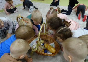 Dzieci zaglądają do koszyczka wielkanocnego.