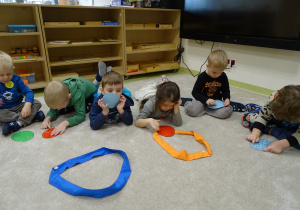Dzieci palcem rysują kształty po linii.