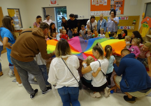 Dzieci z rodzicami bawią się kolorową chustą