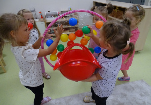 Dziewczynki przyklejają piłeczki do taśmy klejącej przyklejonej do hula-hop